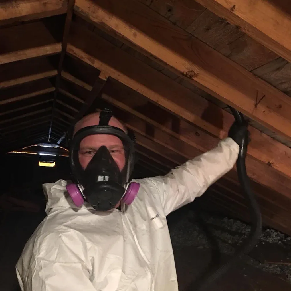 Curtis Berg in a full-face respirator and protective suit, working in an attic